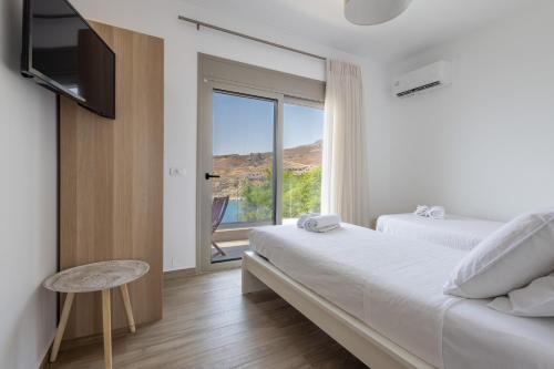 a bedroom with two beds and a sliding glass door at Villa Pava-sea view brand new villa in Archangelos