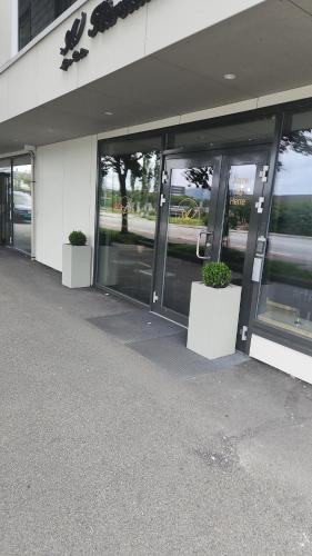 a store front with glass doors and two potted plants at City housing in Stavanger