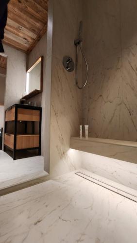 La salle de bains est pourvue d'une douche et d'un mur en marbre blanc. dans l'établissement Les Ô d'Ulysse, à Bourg-Saint-Maurice