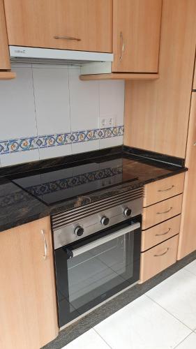 a kitchen with a stove top oven and wooden cabinets at Arenales Azules in Baiona