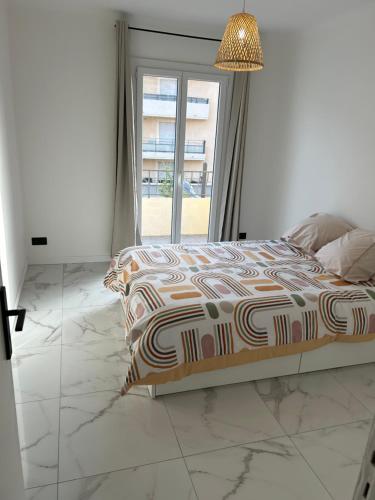 une chambre avec un lit et une grande fenêtre dans l'établissement Appartement moderne, à Cagnes-sur-Mer