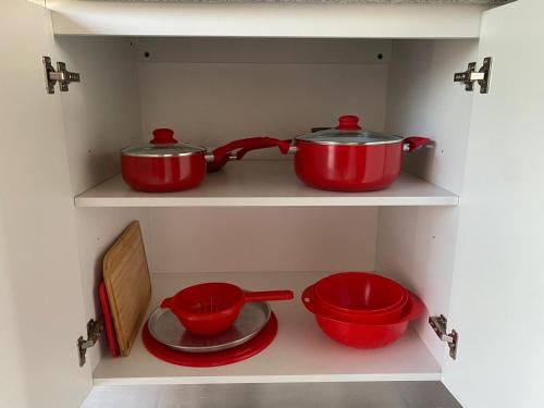 two red pots and pans on a shelf in a kitchen at DEPARTAMENTO VERA MUJICA 1 cochera propia incluida in Rosario