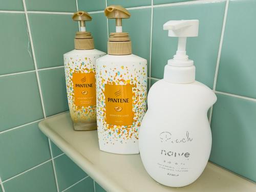 three bottles sitting on a shelf in a bathroom at アワセベイストリートホテル in Okinawa City