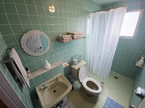 a green tiled bathroom with a toilet and a sink at アワセベイストリートホテル in Okinawa City
