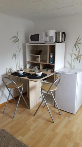 Il comprend une cuisine équipée d'un bureau avec deux chaises et d'un réfrigérateur. dans l'établissement chambre atypique entre mer et collines, à Belgentier