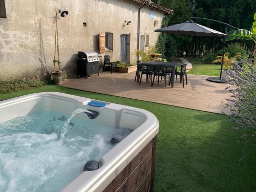 a hot tub in a yard with a table and a patio at Logis Groly gîte avec spa en campagne proche Montauban in Genébrières