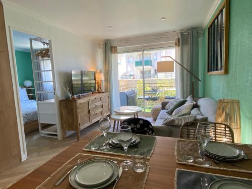 - un salon avec une table et des verres à vin dans l'établissement Chaleureux deux pièce coeur de ville avec parking privé, à Cabourg