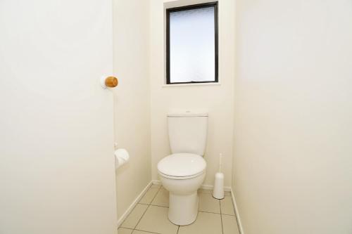 a bathroom with a toilet and a window at Narrows Hideaway - Bookahome in Rukuhia