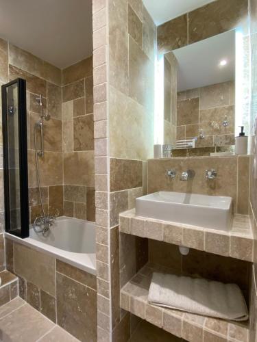 une salle de bain avec un lavabo, une baignoire et un miroir dans l'établissement Chaleureux deux pièce coeur de ville avec parking privé, à Cabourg