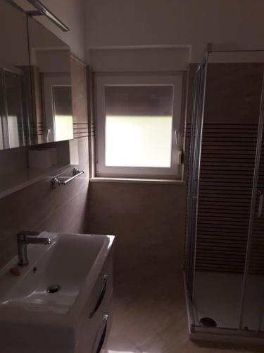 a bathroom with a sink and a shower with a window at Comfortable apartment with the view in Njivice