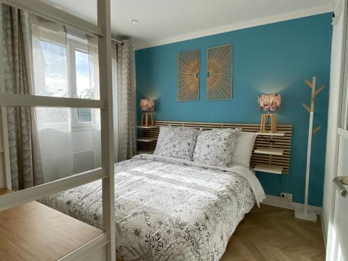 une chambre avec un mur bleu et un lit dans l'établissement Cosy deux pièces coeur de ville avec parking privé, à Cabourg
