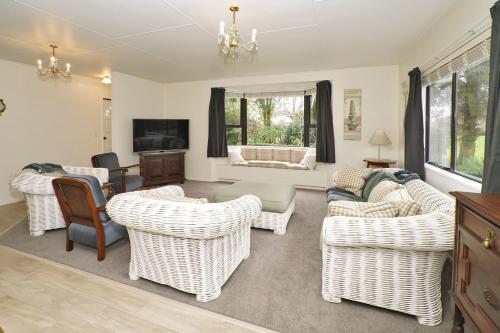 a living room with wicker chairs and a couch at Narrows Hideaway - Bookahome in Rukuhia