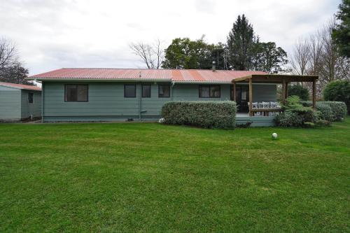 a white house with a red roof on a yard at Narrows Hideaway - Bookahome in Rukuhia