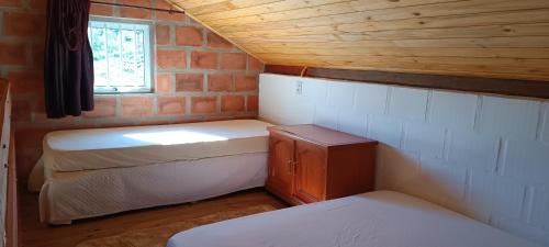 a small room with two beds and a window at Terras de Bragança in Bragança Paulista