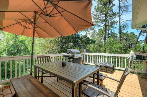 a wooden deck with a table and an umbrella at Canopy Springs Game Room & Covered Outdoor Oasis in Colorado Springs