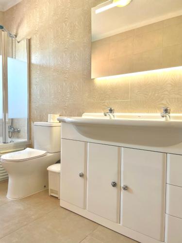 a white bathroom with a sink and a toilet at Colina do Elétrico in Figueira da Foz