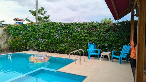 a swimming pool with two blue chairs next to a hedge at Villa Paradise - Mar y Naturaleza in Punta de Piedra