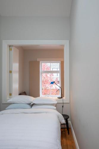 a white bedroom with a bed and a window at The Princes Apartment in Dunedin
