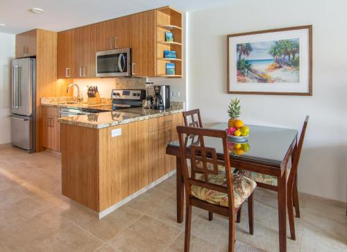 a kitchen with a table and a dining room at Nāpili Surf Beach Resort by Castle in Lahaina