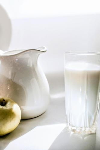 a glass of milk next to a vase and an apple at Guest room in Lucan