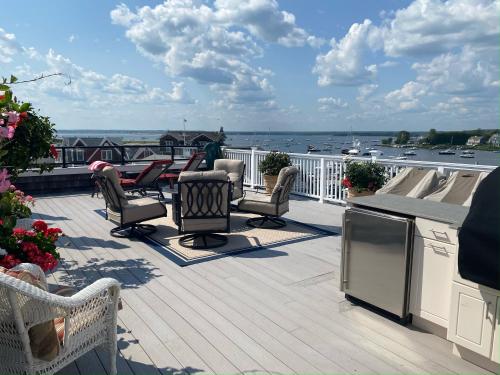 a patio with chairs and tables on a deck at Watch Hill, RI Luxury Penthouse Rental Ocean View & Rooftop Deck in Westerly