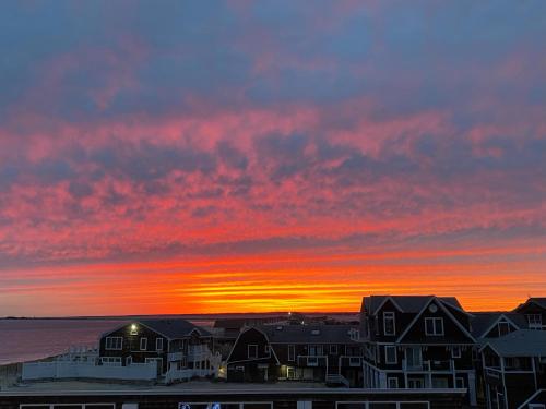 a sunset over a beach with houses and the ocean at Watch Hill, RI Luxury Penthouse Rental Ocean View & Rooftop Deck in Westerly