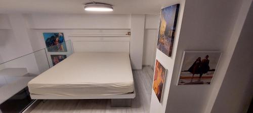 - une petite chambre avec un lit blanc et des photos sur le mur dans l'établissement ARThome Holiday Apartment, à Pescara