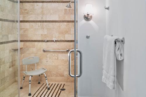 a shower with a chair next to a glass door at Le M&eacute;ridien Mexico City Reforma in Mexico City