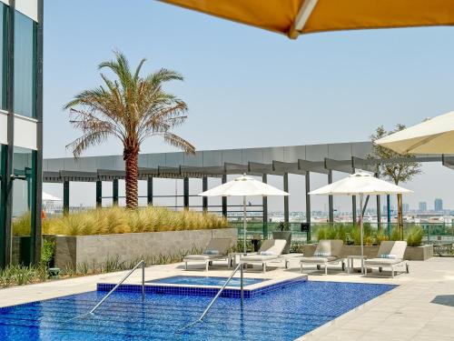 a pool with chairs and umbrellas on a building at Holiday Inn Dubai Business Bay by IHG in Dubai