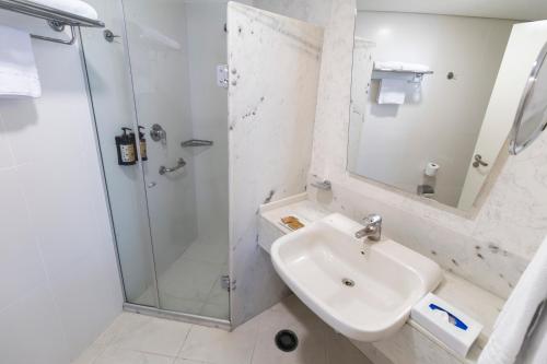 a white bathroom with a shower and a sink at Hotel Nacional Inn Jaragua Sao Paulo in Sao Paulo