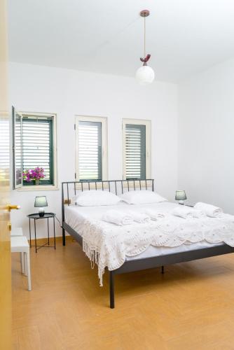 a large bed in a white room with two windows at Twin Villa Tragjas in Vlorë
