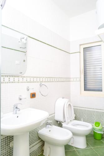a white bathroom with a toilet and a sink at Twin Villa Tragjas in Vlorë