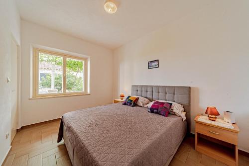 a bedroom with a large bed and a window at Apartments by the sea Lumbarda, Korcula - 4348 in Lumbarda