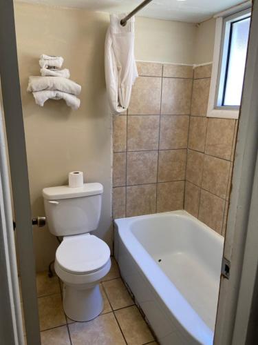 a bathroom with a toilet and a tub and a sink at Glenstone place extended stay motel in Springfield