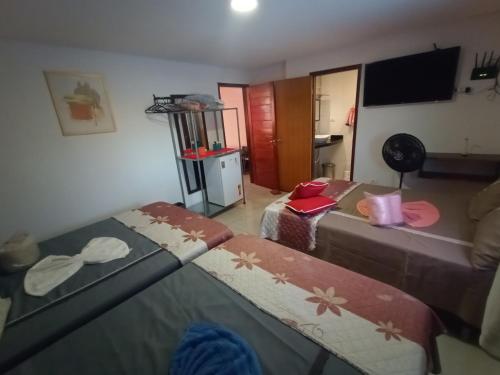 a living room with two beds and a television at Lar Recife Olinda - Hostel com suítes privativas - Prox Centro de Convenções in Recife