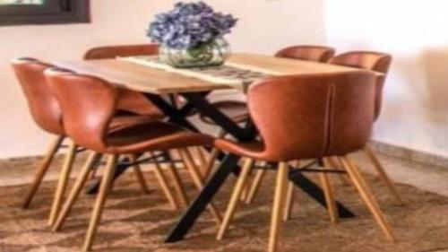 a wooden table with four chairs and a vase of flowers at New Villa Es Novells Illes Balears in Illes Balears