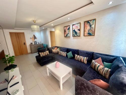 a living room with a blue couch and a table at Zen & Welcoming CFC - Garage & Tramway in Casablanca