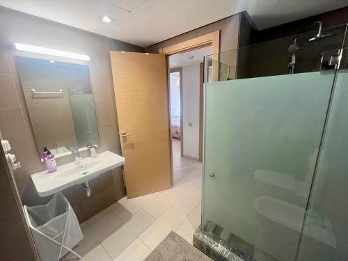 a bathroom with a glass shower and a sink at Zen & Welcoming CFC - Garage & Tramway in Casablanca
