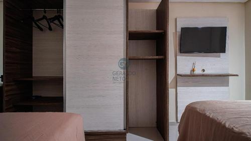 a room with a bedroom with a tv and a bed at Sol, mar e vida noturna in João Pessoa