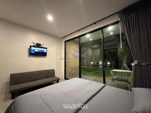 a bedroom with a bed and a tv on a wall at ธีริน ธารา - ที่พักริมแม่น้ำแควใหญ่ (TRIRIN TARA) in Ban Tha Pong (1)