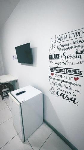 ein weißer Kühlschrank in einem Raum mit einem Schild an der Wand in der Unterkunft Pituba Suítes in Salvador