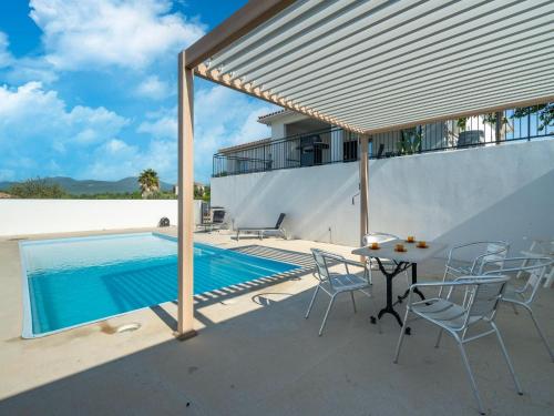 un patio avec une table et des chaises à côté d'une piscine dans l'établissement Villa in Cessenon-sur-Orb with Private Pool, à Cessenon