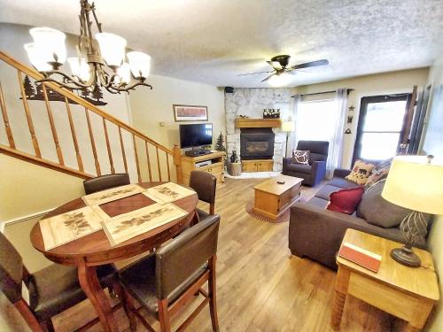 un soggiorno con un tavolo e un divano di Valley Condo 111 - Dancing Bear Retreat - Creekside - WiFi - Hot Tub - Fireplace - Washer - Dryer - Playground a Red River