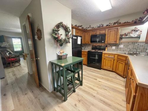 una cucina con tavolo verde in una camera di Valley Condo 112 - Creekside - WiFi - Pet Friendly - Hot Tub - Fireplace - Washer - Dryer - Playground a Red River