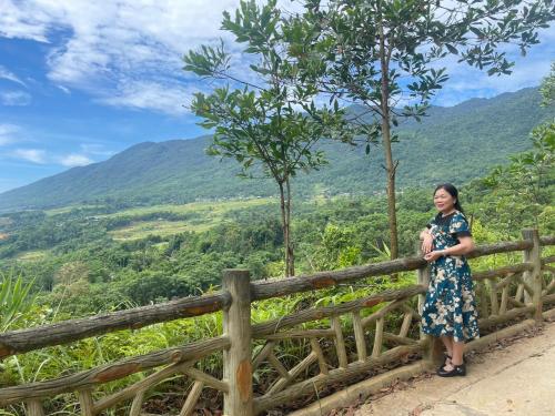 a woman standing on a fence overlooking a valley at Pù Luông Sala Homestay in Hương Bá Thước