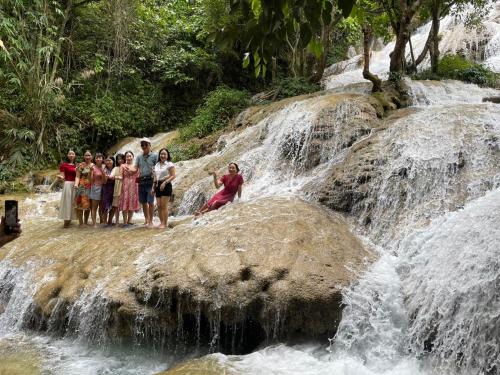 a group of people standing on a rock near a waterfall at Pù Luông Sala Homestay in Hương Bá Thước