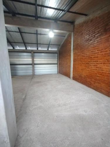 an empty garage with a garage door and a brick wall at Las Dos Tinajas in La Punta