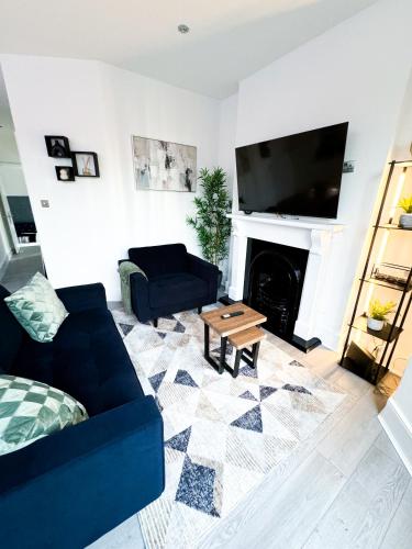 a living room with a blue couch and a fireplace at The Cosy Catford Apartment - 2bd in Catford