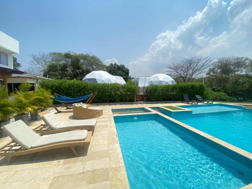 a swimming pool with chaise lounge chairs next to a house at Hotel Aqua House in Tubará