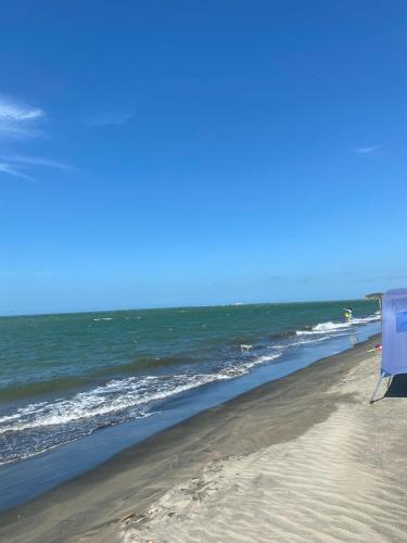 a beach with a blue umbrella and the ocean at Hotel Aqua House in Tubará